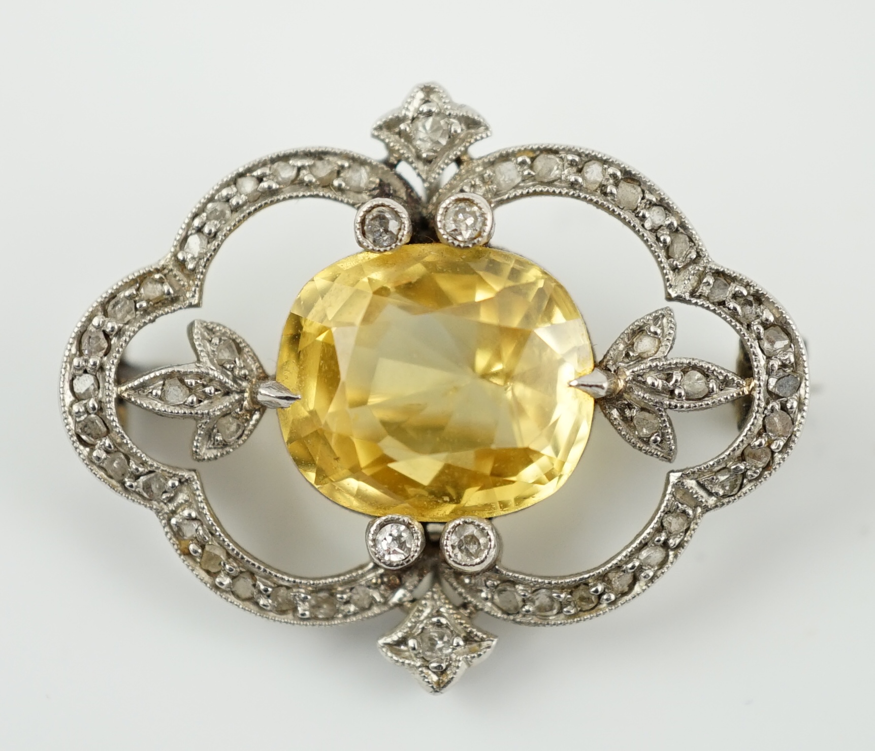 A Belle Epoque white gold, single stone yellow sapphire and diamond chip cluster set open work brooch